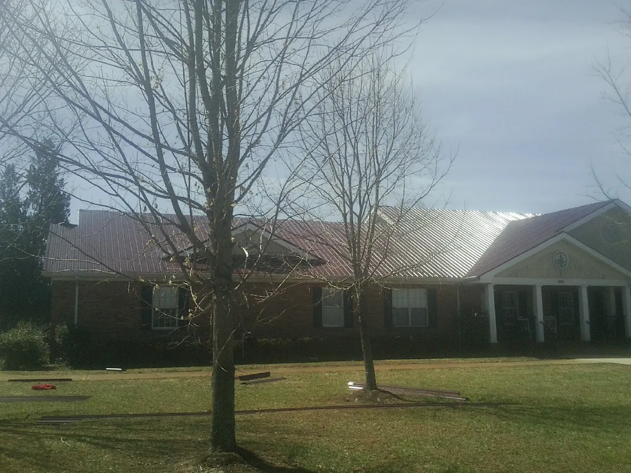 Red metal roof on a brick building seen from the front lawn in Waterford